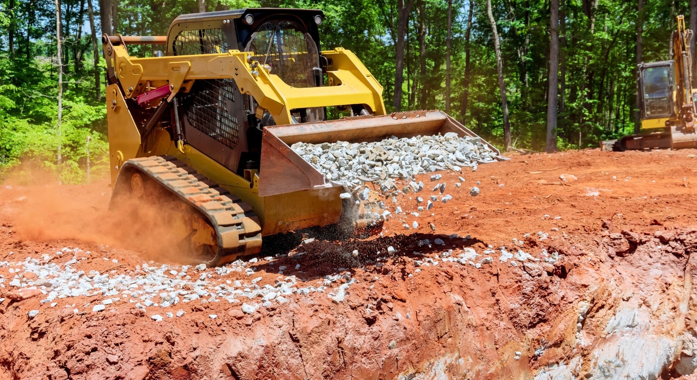 a bobcat hauling construction rock in the bucket