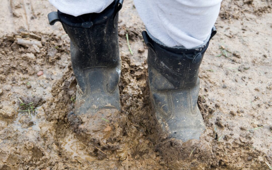 man wearing rain boots in the mud