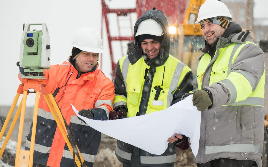three men looking over blueprints in winter outside